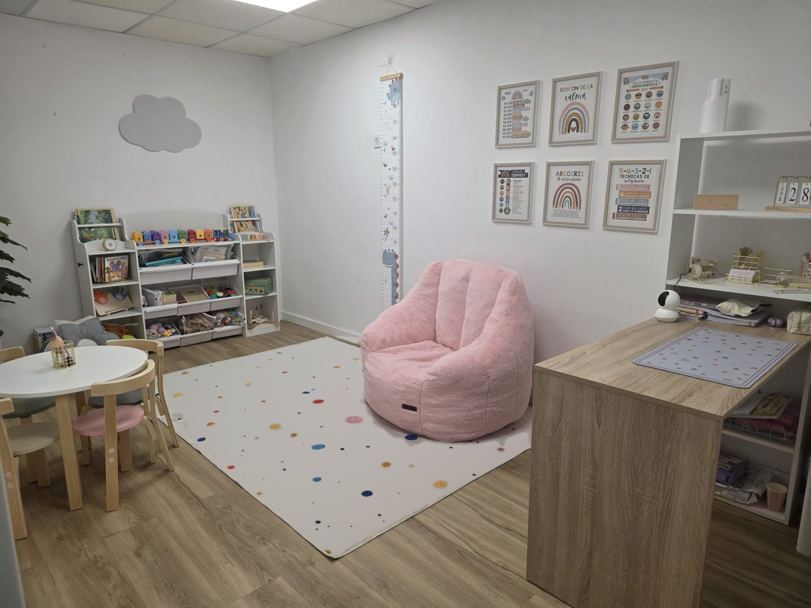 Sala de trabajo de Desde su Mundo: mesa infantil, estantería con juegos, rincón de la calma con un sillón rosa